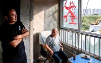 Shi Tieniu, 39 och Guo Changyuan, 78 sitter och samtalar i ett sällskapsrum i den ofärdiga byggnaden.