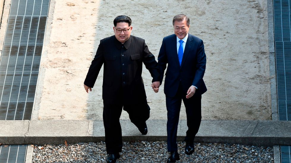 Kim Jong-Un och Sydkoreas president Moon Jae-In håller hand när de tar steget in i Sydkorea