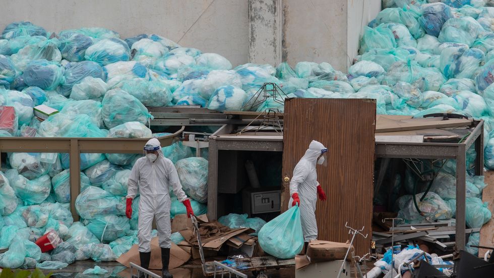 Vårdarbetare i skyddsutrustning slänger sopor utanför ett sjukhus i delstaten Veracruz i Mexiko, där covid-patienter behandlas.