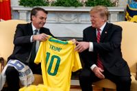 Brasiliens förre president Jair Bolsonaro har ett varmt förhållande med Donald Trump. Här ses Bolsonaro överlämna en brasiliansk fotbollströja till Trump under ett besök i Vita huset 2019.