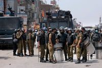 Poliser samlas efter sin insats vid de våldsamma protesterna i söndags i Lahore.