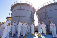En av tusentals behållare av förorenat vatten vid Fukushimas kärnkraftverk i Japan (här med Japans premiärminister Shinzo Abe, röd hjälm). Nu öppnar regeringen och energibolaget som äger kärnkraftverket för att börja släppa ut det förorenade vattnet i havet. Arkivbild.