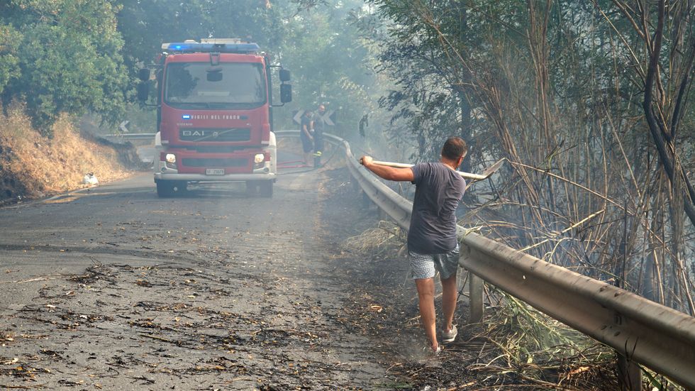 En frivillig brandbekämpare bistår i arbetet mot lågorna i Fuscaldo i regionen Kalabrien i onsdags.
