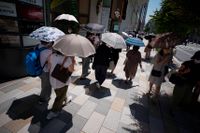 Människor tar skydd från solen under paraplyer i Tokyo den 28 juni. Arkivbild.