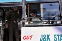 Polis inspekterar bussen som träffades av granaten i Jammu. 