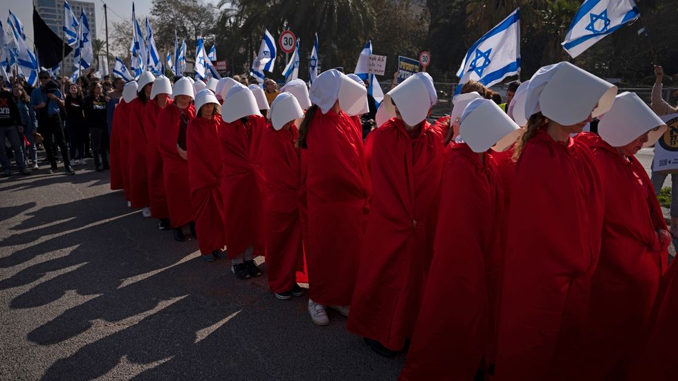 Demonstranter för kvinnors rättigheter klädda i rött och med vita hättor som en referens till tv-serien "The handmaid's tale". De protesterar under måndagen i Tel Aviv mot regeringens planer på att ändra rättsväsendet.