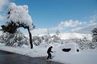 En man skottar bort snö utanför sitt hus i Aten-förorten Dionysos på onsdagen, efter de senaste dagarnas sällsynt kraftiga snöfall.