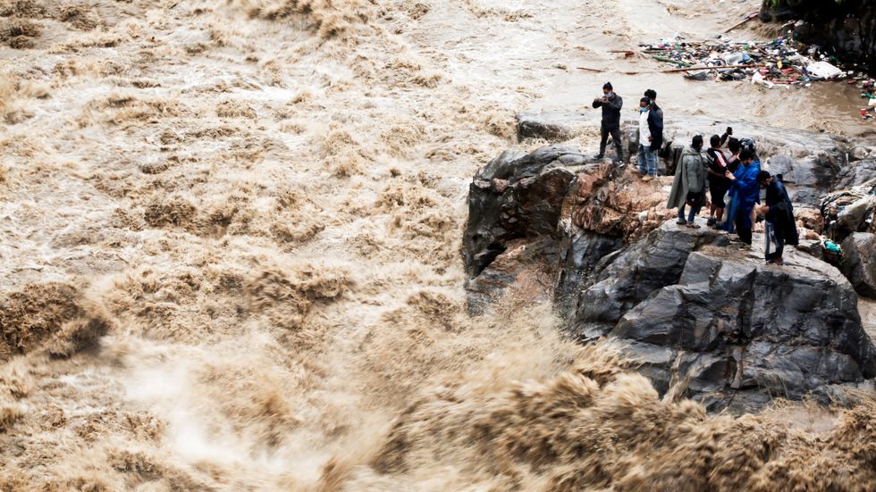 Nepaleser tar foton på Bagmatifloden i huvudstaden Kathmandu. Jordskred och översvämningar har blockerat motorvägen som förbinder staden med resten av landet.