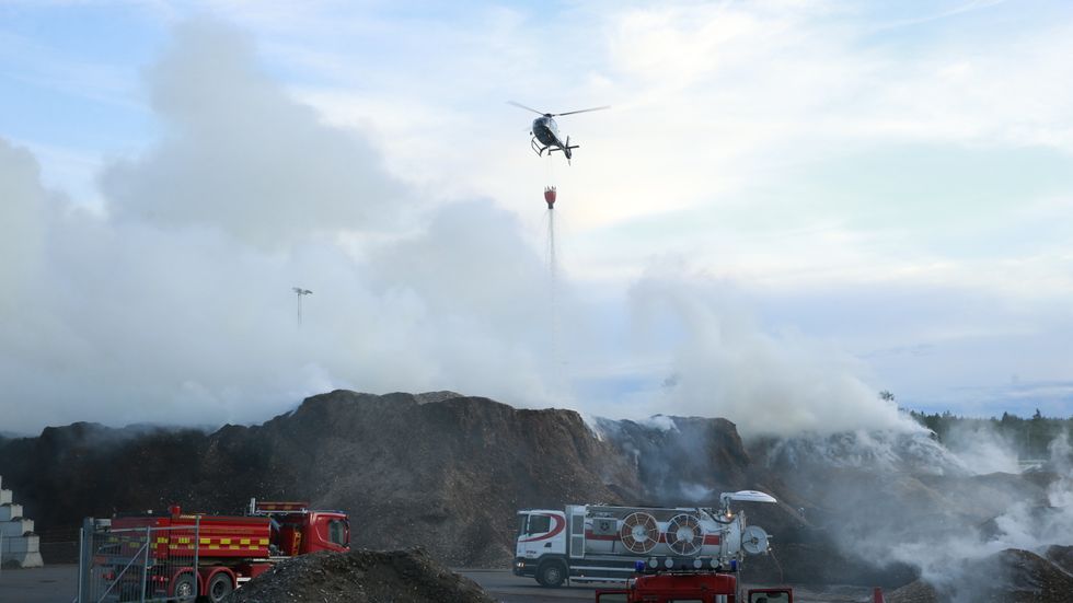 En brand i en flishög i Nykvarn i Stockholms län vattenbombas sedan den utvecklats till en skogsbrand.