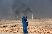 En kvinna bär sitt barn på en väg i utkanten av Kabul.
