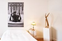 Zanele Muholi, ”Bona, Charlottesville” hänger ovanför sängen. Till höger står Theresa Traoré Dahlbergs skulptur ”Haren Hakili”.