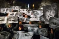 Människor håller upp fotografier av de mördade tecknarna på Union Square i New York.