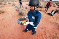 En medarbetare på Jaxa hämtar kapseln med asteroidstoft som landade i en öken i Australien.