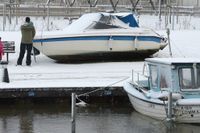 Nyfikna tittar på en båt som slitit sig har blivit stående på på kajen bredvid med fören mot en papperskorg i hamnen i Lomma sedan vattnet sjunkit undan efter stormen Sven på lördagen.