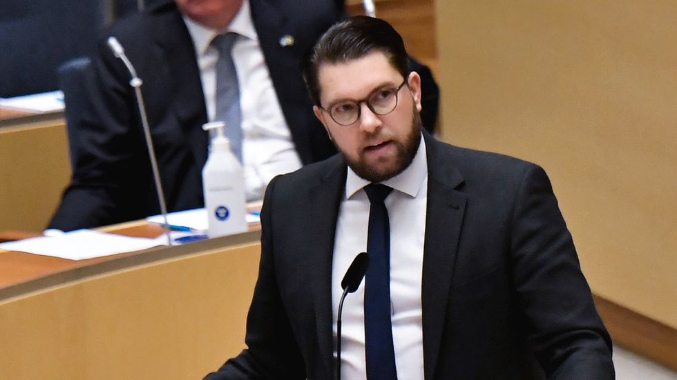 Jimmie Åkesson talar i riksdagen. Stefan Löfven i bakgrunden.
