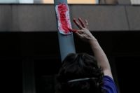 En blodig binda äcklar och provocerar. Här smetar en kvinna röd färg på en binda vid en protest mot Brasiliens president Jair Bolsonaro. Arkivbild.