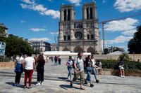 Människor på torget framför Notre-Dame år 2020, ett år efter branden som nästan ödelade det historiska landmärket i Paris.