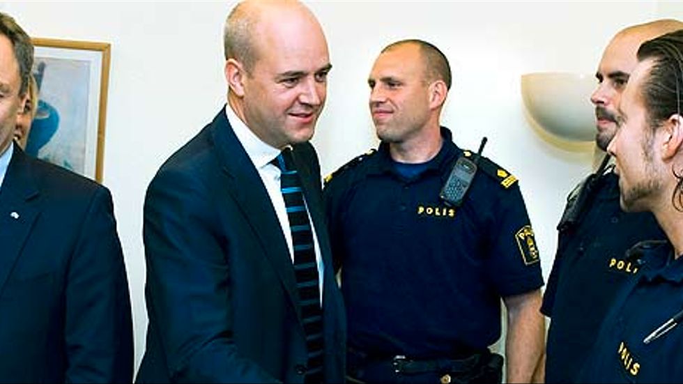 Statsminister Fredrik Reinfeldt hälsar på polisman när alliansens partiledare på tisdagen besökte poliskontoret i Stockholmsförorten Hallunda där de presenterade en miljardförstärkning till rättsväsendet. Till vänster Jan Björklund, Folkpartiet.