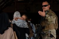 En amerikansk soldat visar vägen för afghaner ombord på ett flygplan. 