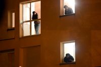 Asylsökande i Frankrike tittar ut på polisen utanför huset som dom ockuperat i Pace. Fransk polis vräkte 250 asylsökande från i huvudsak östra Europa och Afrika under veckan.