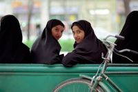 Unga muslimska kvinnor vid en busshållplats i Esfahan, Iran.