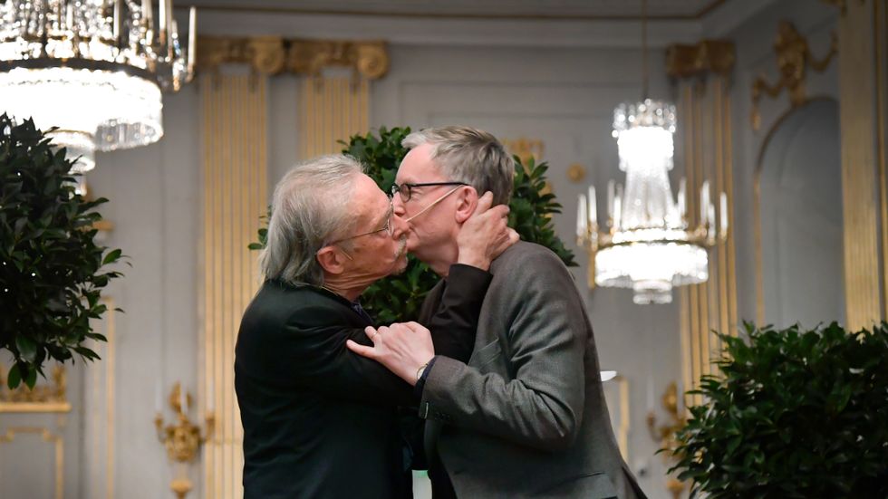 Nobelpristagaren Peter Handke kysser Anders Olsson, ordförande i Nobelkommittén, vid en presskonferens i Stockholm.