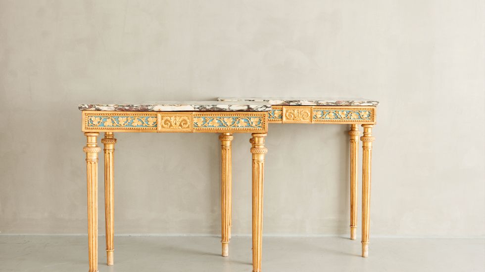 Konsolbord med skuren och förgylld dekor. Skivor av marmor från Breccia i Italien. Rokokotidens rundande ben rätas ut och förses i stället med stram kannelyr.