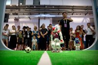 Besökarna på världsrobotkonferensen tittar på en fotbollsmatch mellan robotar.