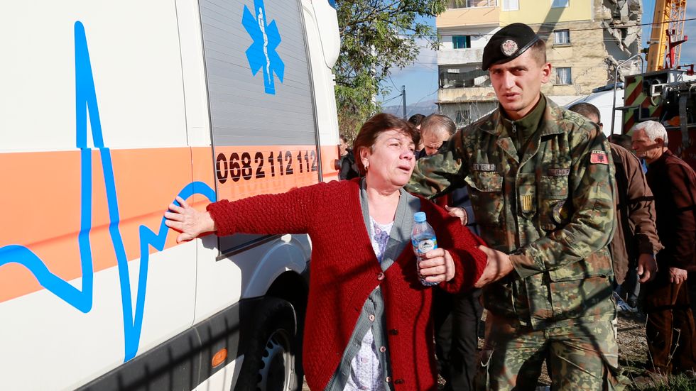 En soldat som kallats in tar hand om en kvinna intill en raserad byggnad efter jordbävningen som uppmätte 6,4 på Richterskalan. 