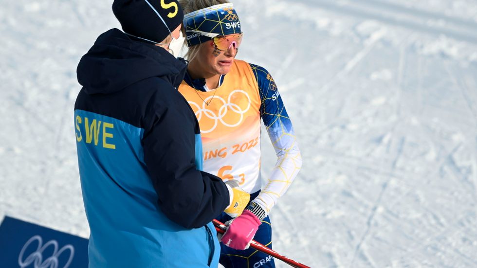 Frida Karlsson tröstas av en svensk ledare efter tredje sträckan i damstafetten.
