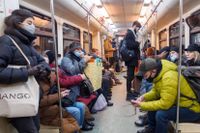 Resenärer bär munskydd på tunnelbanan i Moskva.