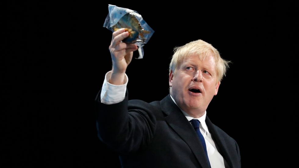 Storbritanniens permiärminister Boris Johnson, håller upp en rökt fisk under ett tal.