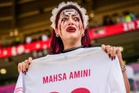 En iransk supporter gråter medan hon håller upp en fotbollströja med namnet på den 22-åriga Mahsa Amini, som slogs ihjäl av den iranska moralpolisen.