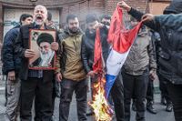 Iranska män bränner franska flaggan utanför Frankrikes ambassad i Teheran i protest mot satirtidningen Charlie Hebdos karikatyrer.