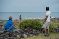 Tre män söker efter vrakdelar vid stranden Saint-Andre på ön Réunion.