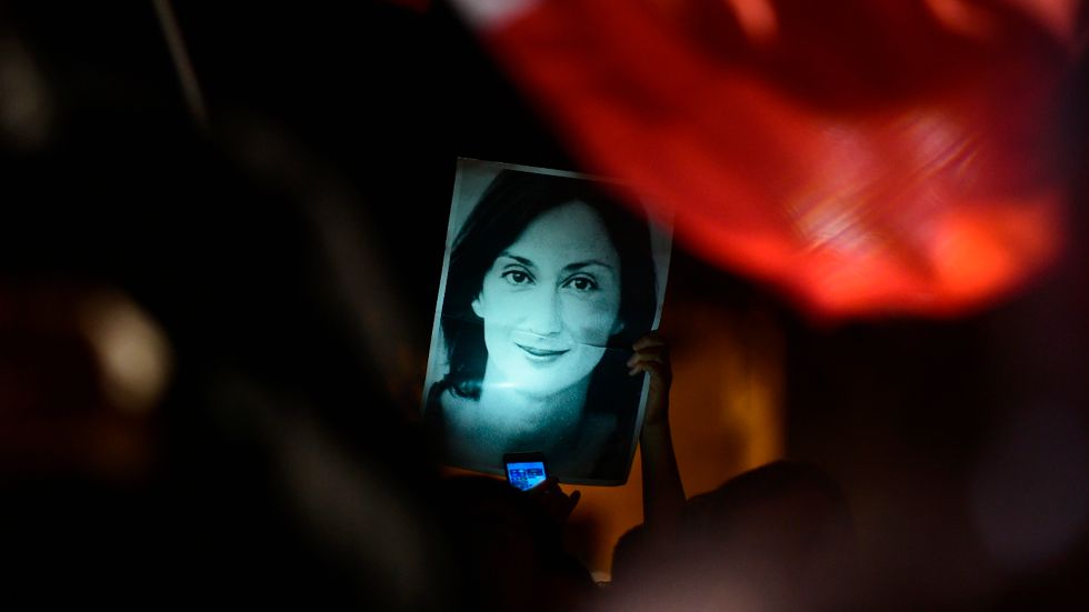 En demonstrant håller upp en bild på den mördare reportern Daphne Caruana Galizia vid en demonstration 2019.