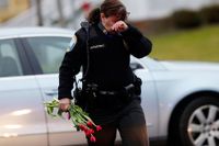 Polisen Maryhelen McCarthy bär med sig blommor för att hedra offren.