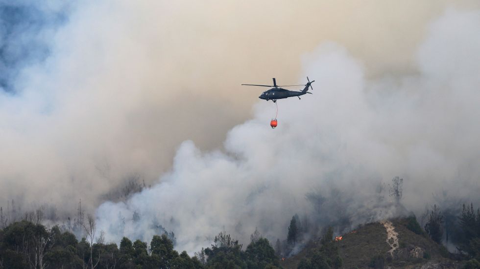 En helikopter vattenbombar en skogsbrand i Colombia. Arkivbild.