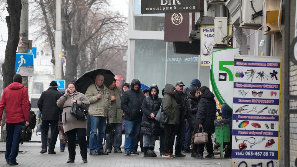 Människor köar för att ta ut pengar i Zaporizjzja i Ukraina på fredagen.
