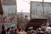 Östtyska gränsvakter syns bakom delar av Berlinmuren när den rivs ner av demonstranter den 11 november 1989.