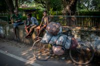 Raju, till vänster i grön t-shirt, tar en paus tillsammans med andra arbetare. Cykeln är lastad med kol som ska transporteras till köpare i Dhanbad i östra Indien.