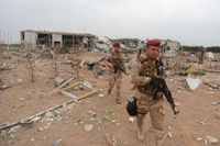 Irakiska soldater inspekterar en flygplats som förstördes i en amerikansk vedergällningsattack efter angreppet på Tajibasen den 11 mars.