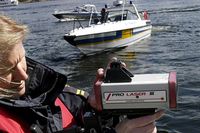 Kustbevakaren Karin Andersson visar en hastighetsmätare. I bakgrunden en av KBV:s Cobra-båtar.