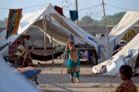 En flicka leker utanför tältet i ett evakueringsläger i Pakistan efter de omfattande översvämningarna i landet.