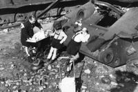 Tyska barn leker med dockor vid vraket av en stridsvagn i Berlin 1948.