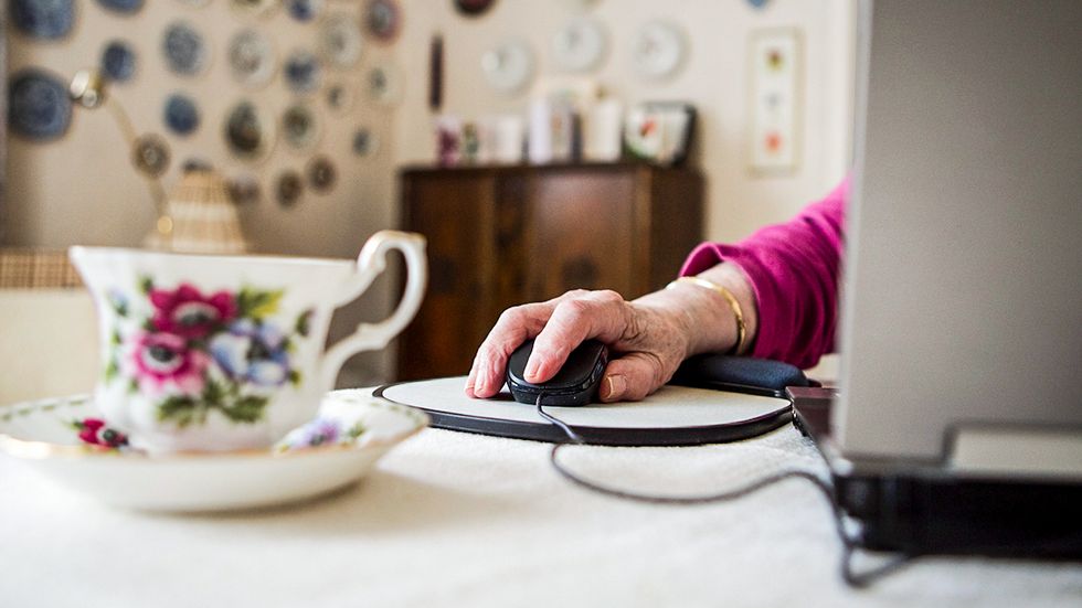 Äldre kvinna betalar räkningar på bärbar dator.