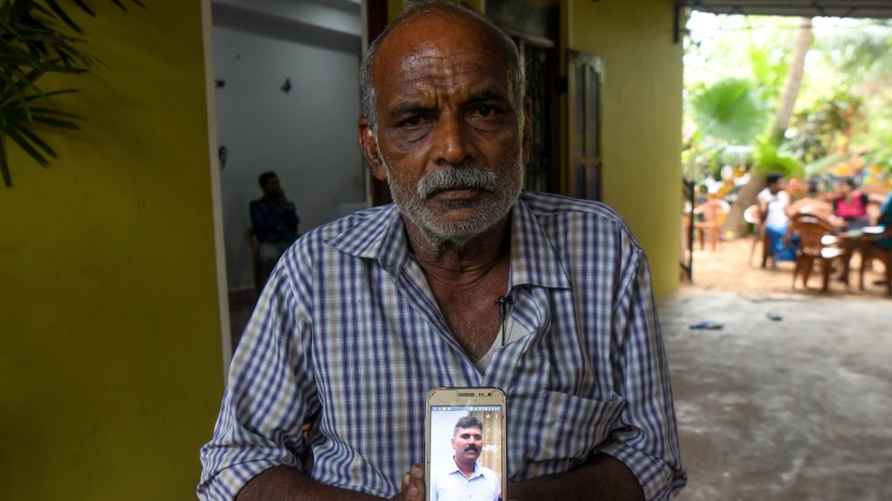 Velusami Raju håller upp en bild på sin telefon av sin son Ramesh Raju som dog i ett av attentaten.