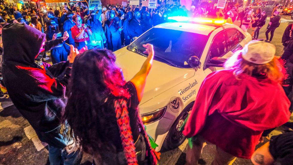 Demonstranter omringar en polisbil.