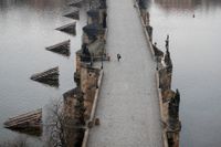 En kvinna promenerar över en nästintill tom Karlsbro i Prag i mars.