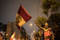En anhängare till Perus president Martín Vizcarra med landets flagga efter att presidenten upplöst kongressen på måndagskvällen lokal tid.